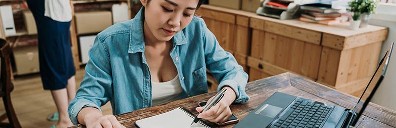 Female entrepreneur working on her business plan using LivePlan's new AI-powered features.