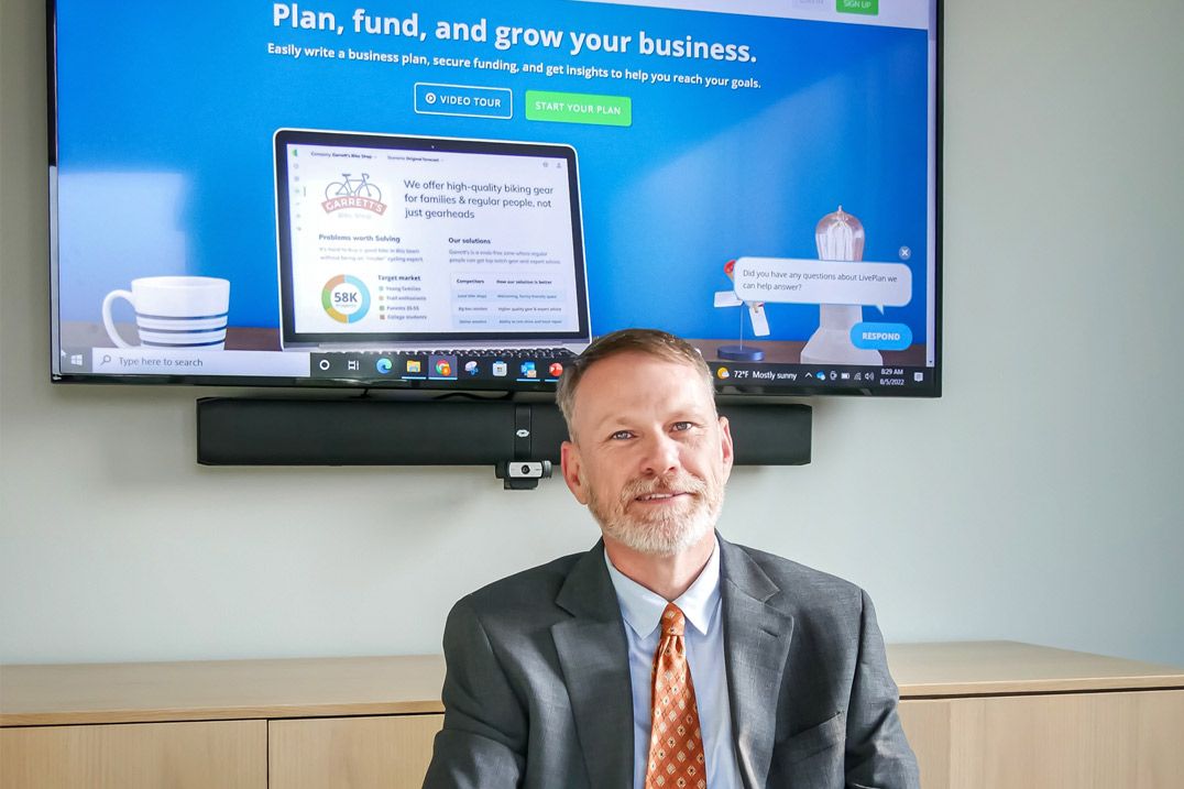 An image of Ben Calhoun of Clemson Small Business Development Center with a monitor behind him displaying the LivePlan website