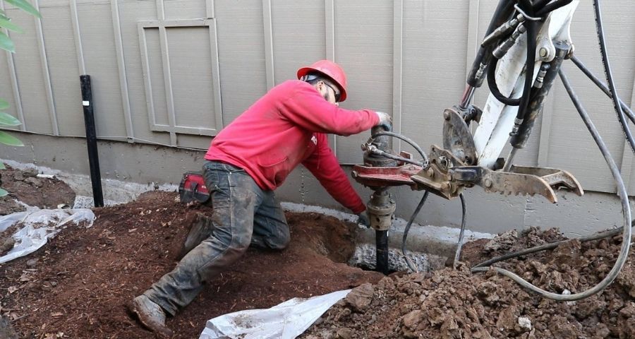 A Ram Jack West employee working on the foundation of a house