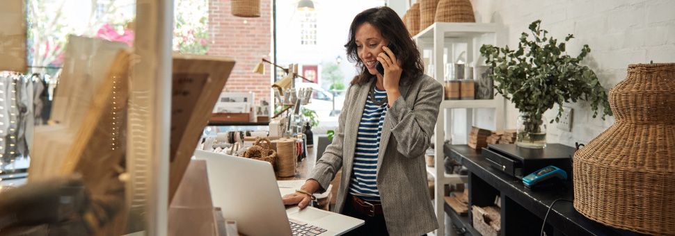 Woman working on phone with laptop in store