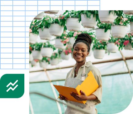 Woman reviewing market research beneath hanging plants in her nursery